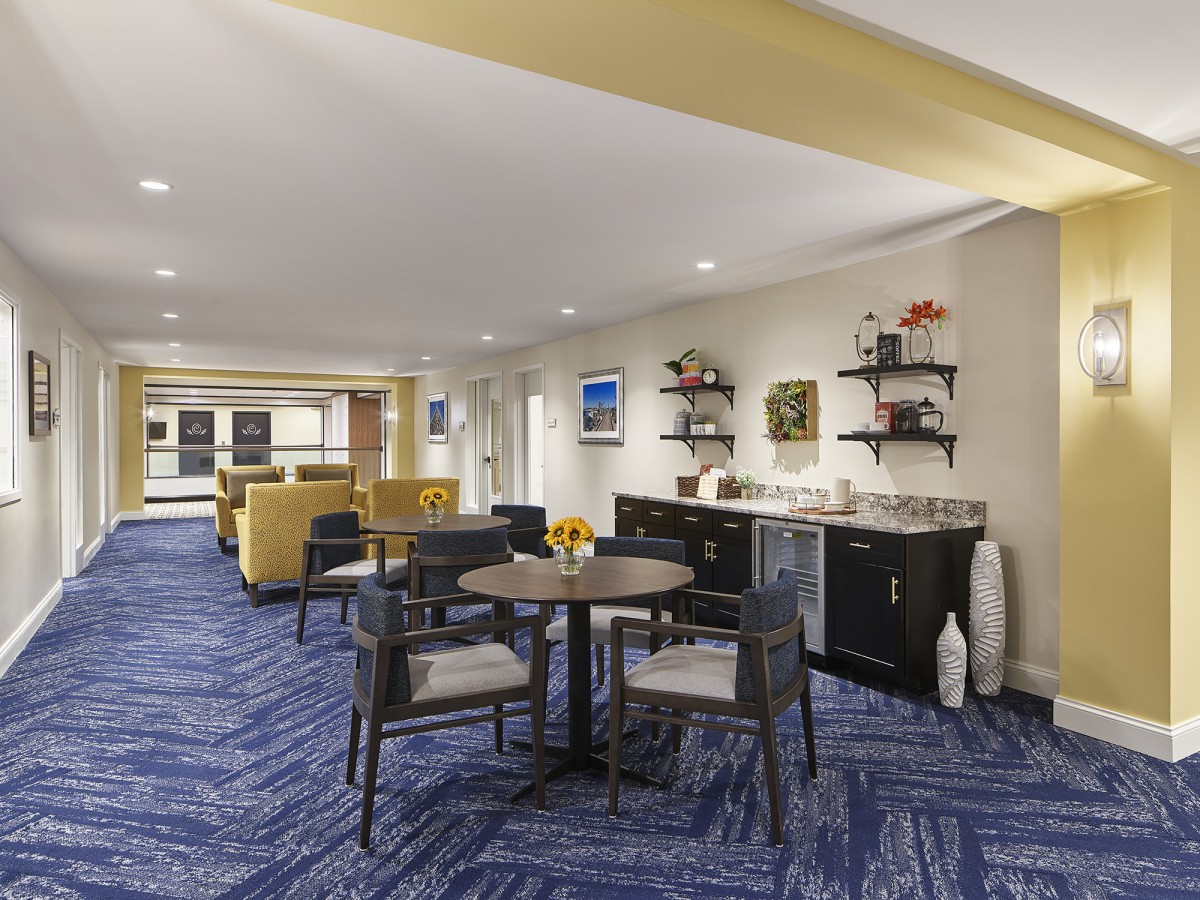 A spacious lounge area with seating, tables, and decorative elements on a blue carpet.
