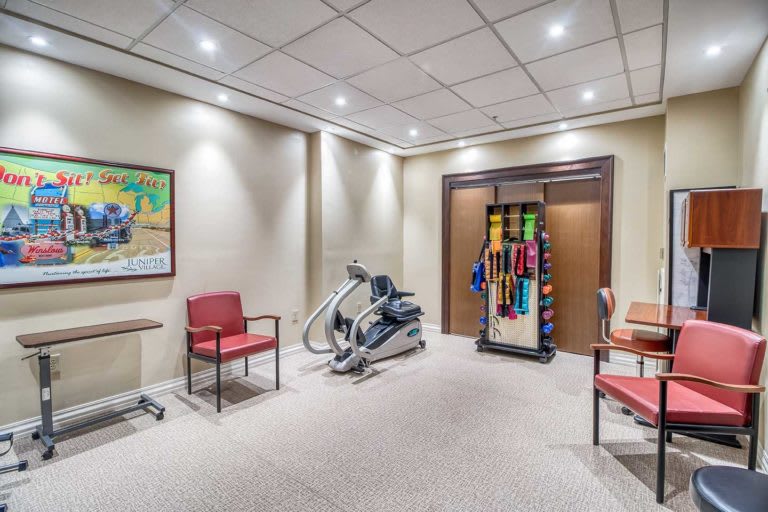 A well-lit room with gym equipment and seating for exercise.