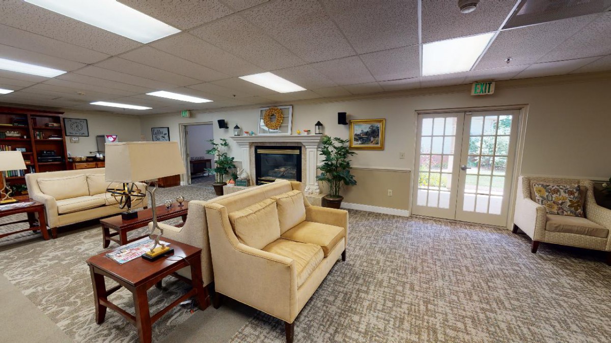 A cozy lobby area with a sofa and fireplace, decorated with plants and artwork.