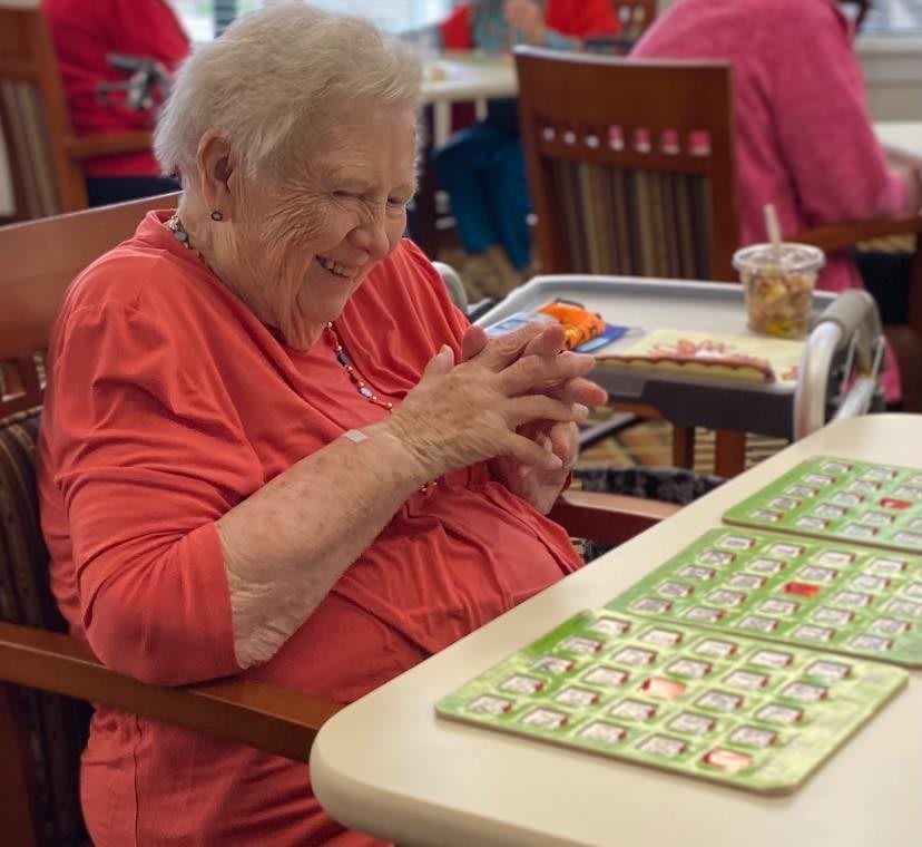 An elderly woman enjoying a game of bingo at a senior center.