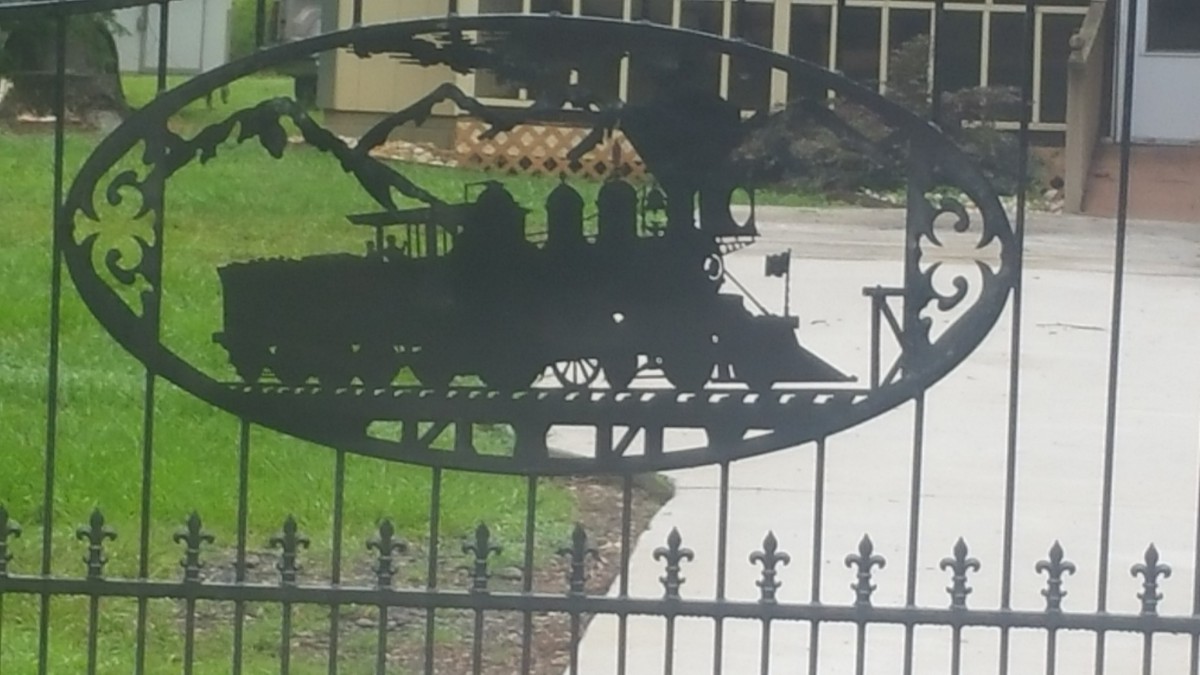 Silhouette of a train in metalwork on an outdoor fence.