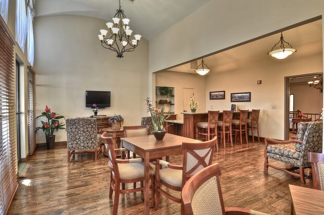An elegant dining area featuring wooden furniture, a chandelier, and a bar counter with seating.