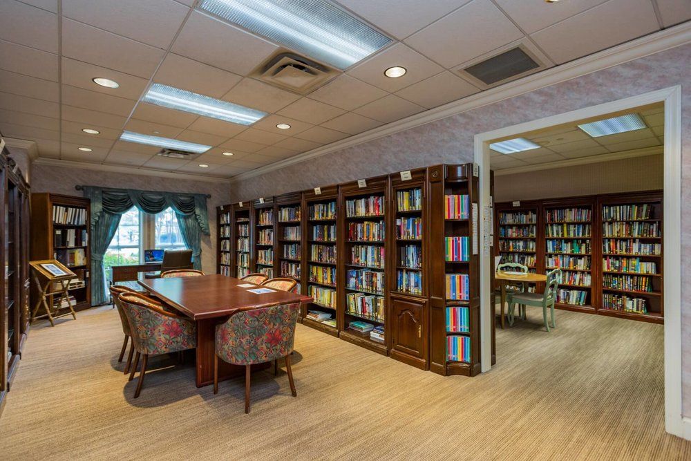 A cozy library with bookshelves and a reading area featuring a table and chairs.