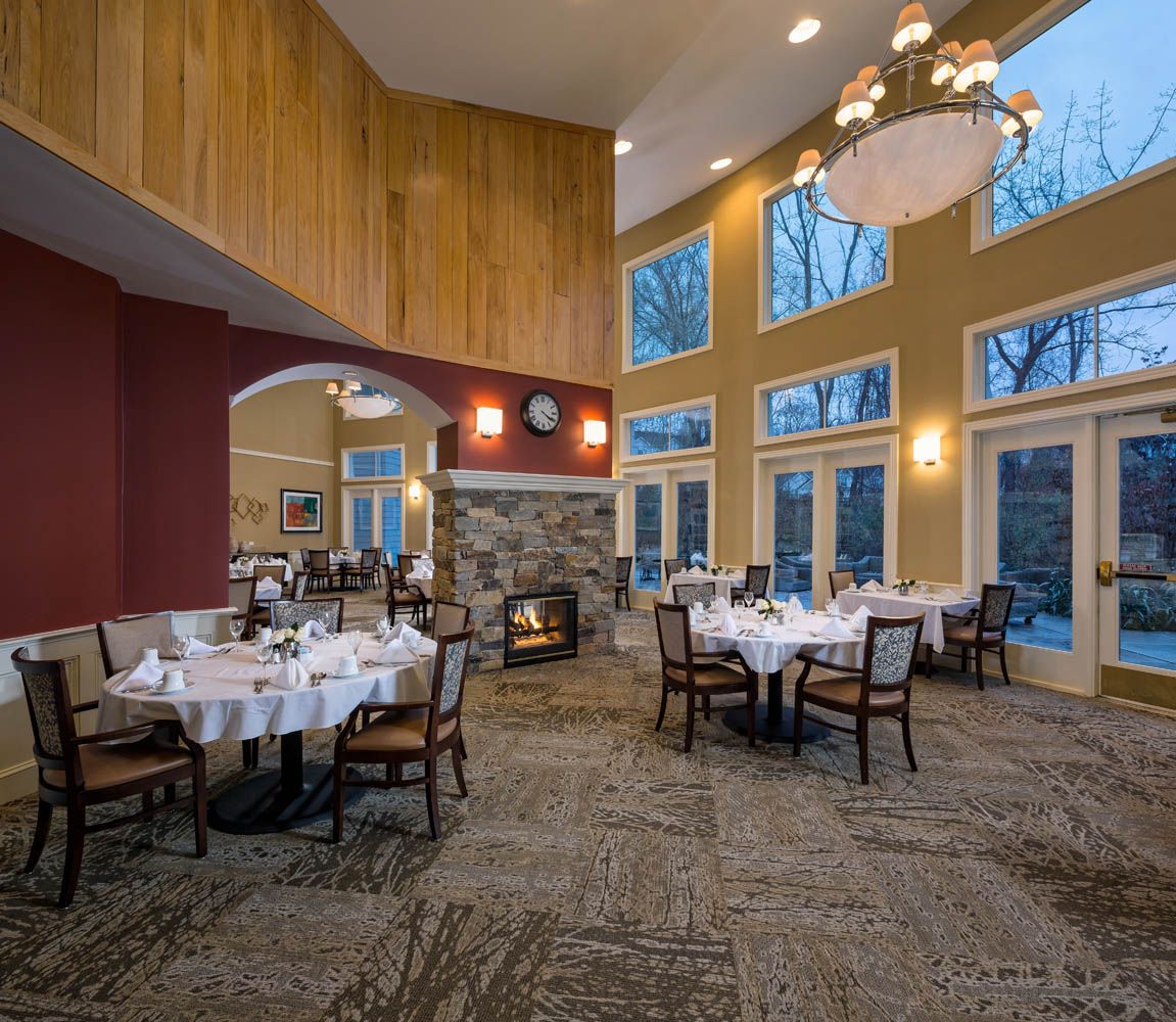 A cozy restaurant dining room with elegantly set tables and a warm fireplace.