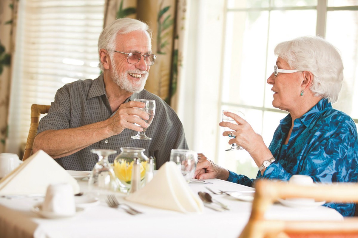 An elderly couple enjoying a conversation over a meal at a restaurant.