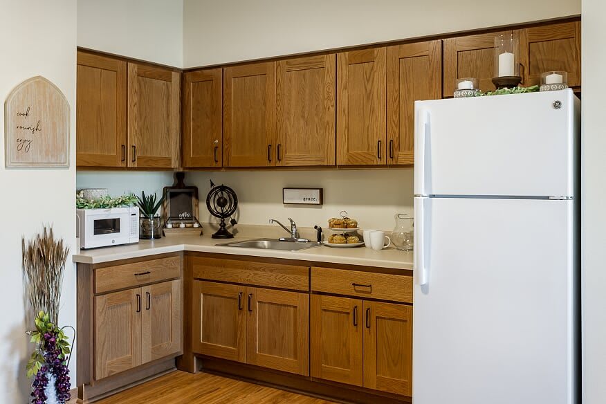A cozy kitchen with wooden cabinets, a white refrigerator, and various appliances on the countertop.