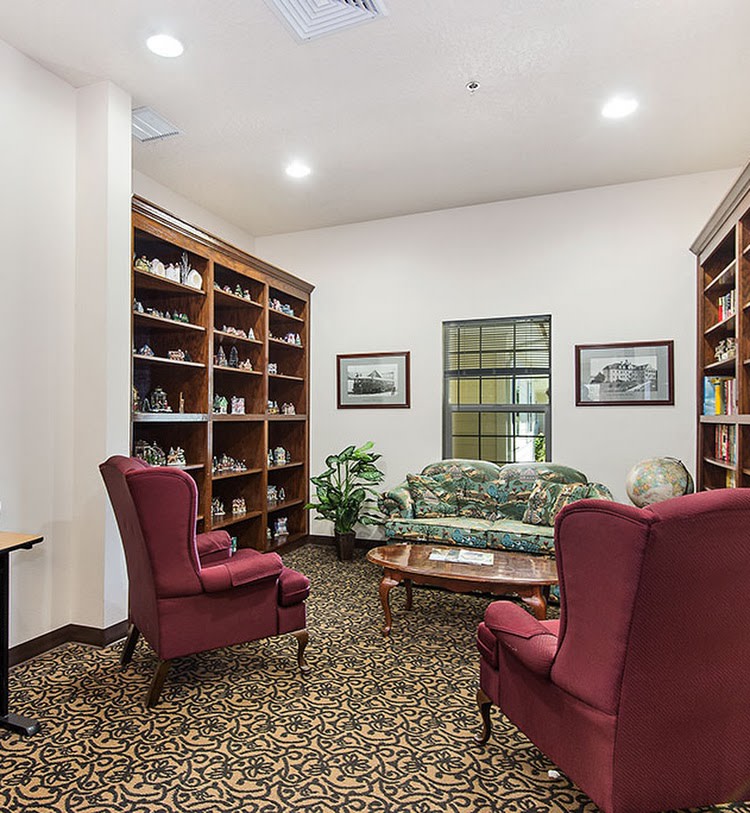 A cozy library room with armchairs and bookshelves.