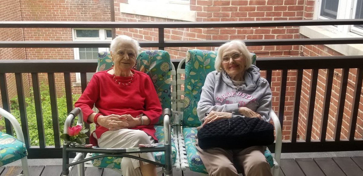 Two elderly women sitting on a balcony enjoying a peaceful moment together.