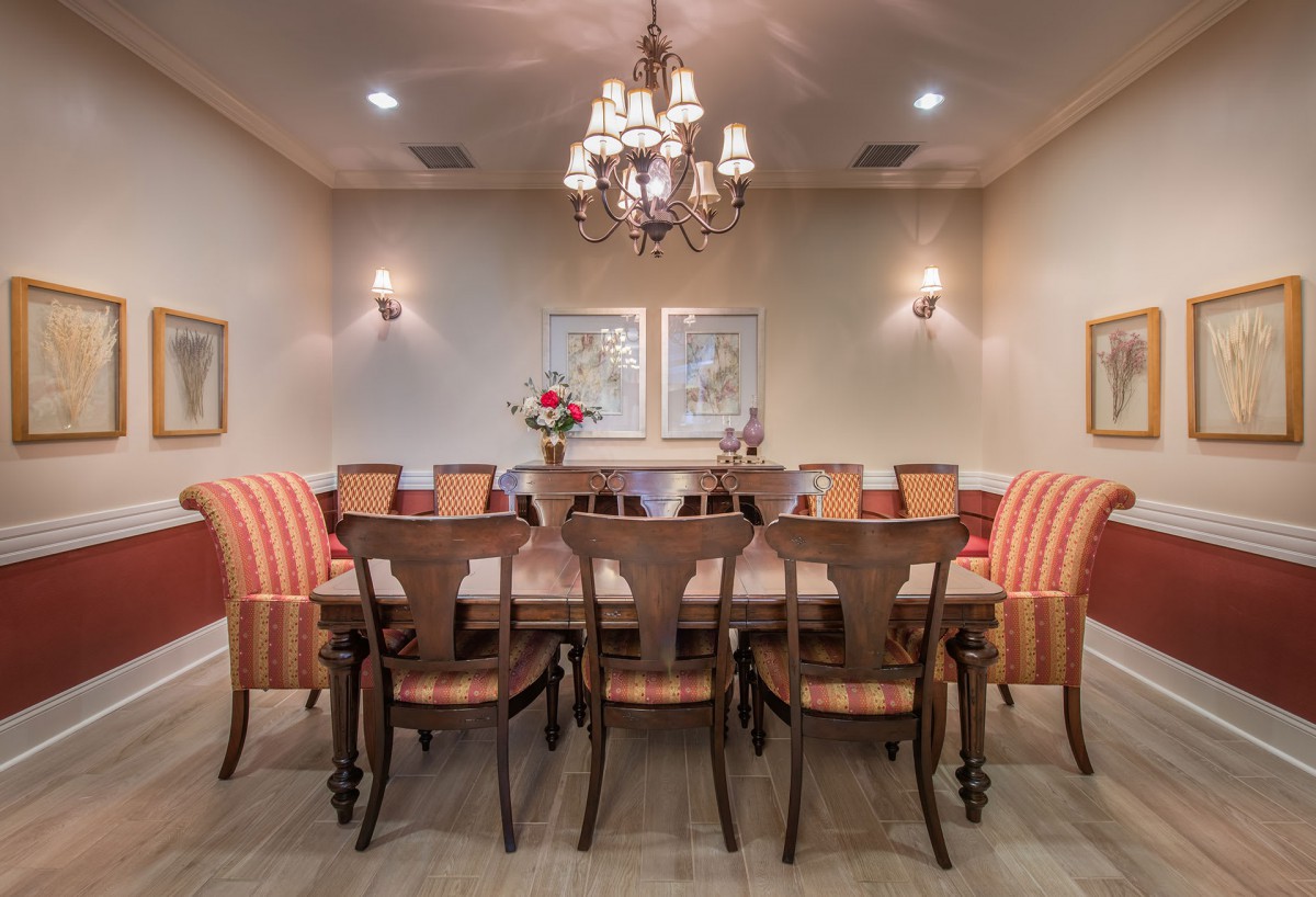 A beautifully decorated dining room featuring a long table and matching chairs under an elegant chandelier.