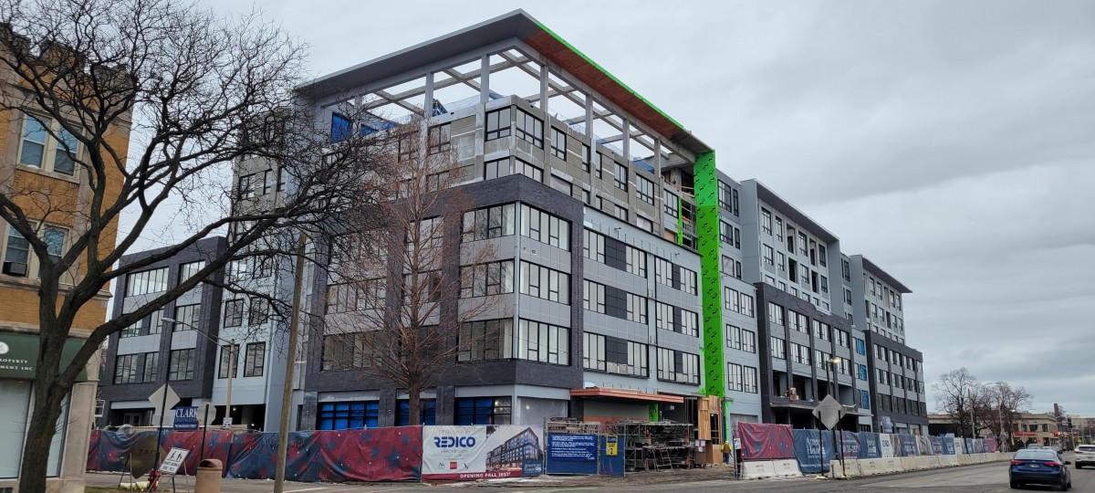 A modern building under construction with scaffolding and cranes.