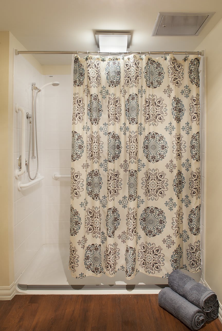 A bathroom shower with a decorative curtain featuring a floral pattern.