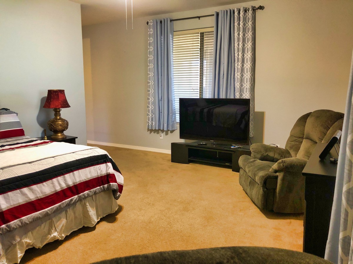 Cozy bedroom with a large bed, armchair, and television.