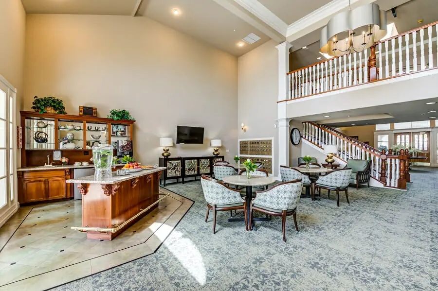 A spacious living room with elegant decor, featuring a staircase, multiple seating areas, and high ceilings.