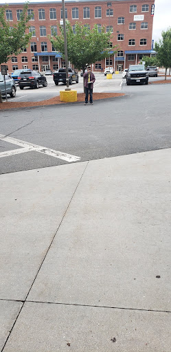 A person standing in a parking lot with vehicles nearby.
