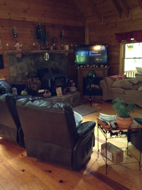 A cozy living room with a rustic cabin vibe, featuring a fireplace and a television.