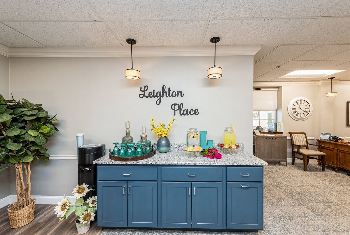 A modern kitchen setup featuring blue cabinets, pendant lighting, and a beverage station.