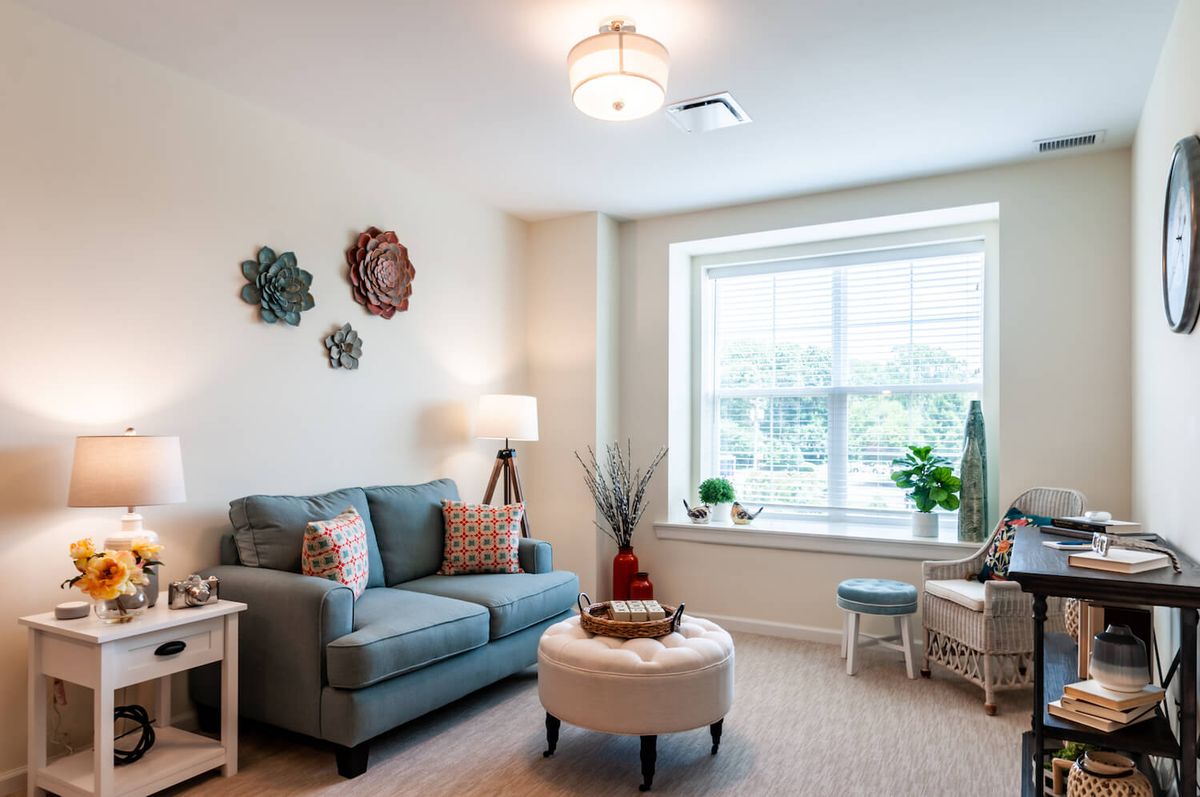 A cozy and modern living room with a sofa, wall decor, and a large window allowing natural light.