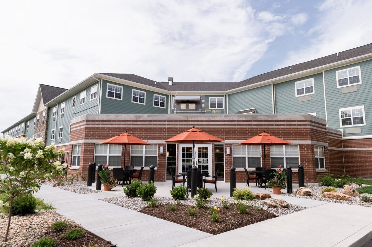A modern residential apartment complex with outdoor seating and landscaped surroundings.