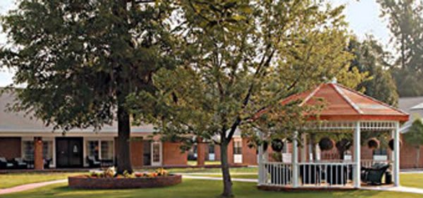 A scenic park area with trees, a gazebo, and nearby buildings.