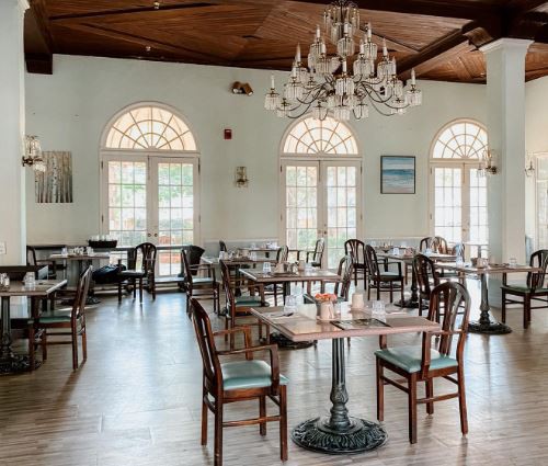 An elegant restaurant interior with a chandelier, featuring neatly arranged tables and chairs.