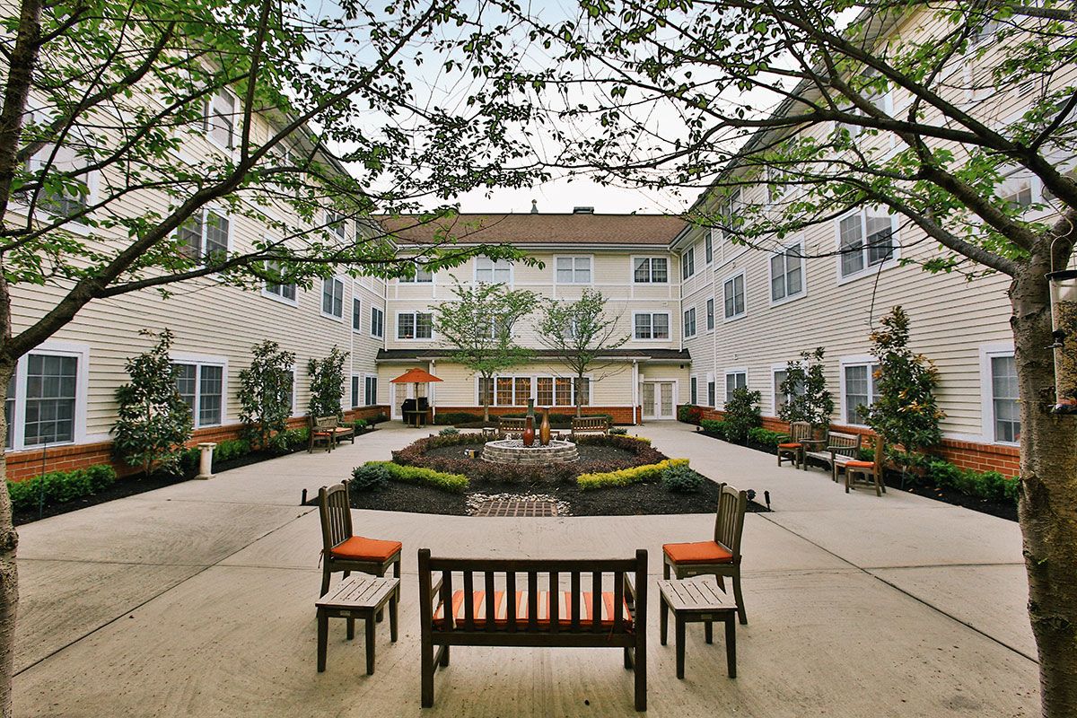 A peaceful courtyard with benches and greenery surrounded by a building.