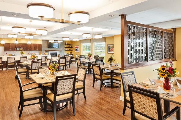 A spacious and elegantly designed dining area with well-arranged tables and chairs, illuminated by stylish lighting fixtures.