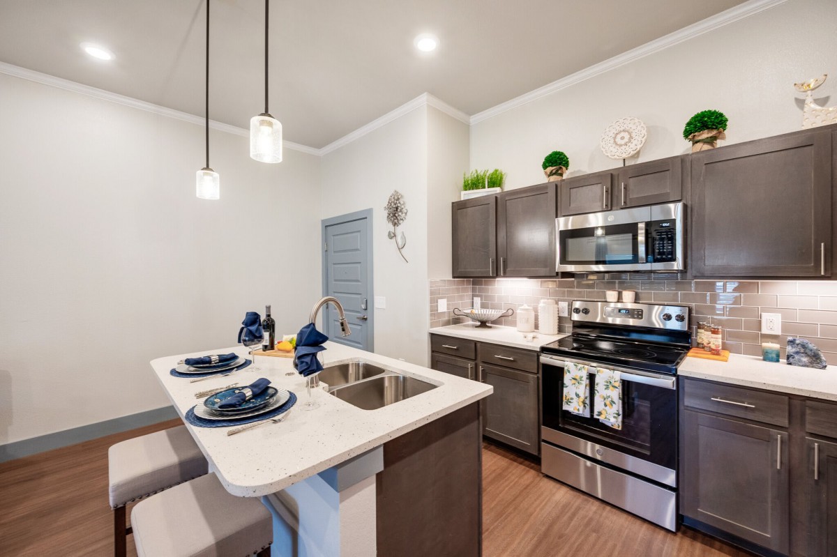 A modern kitchen with stainless steel appliances and a sleek countertop with bar seating.
