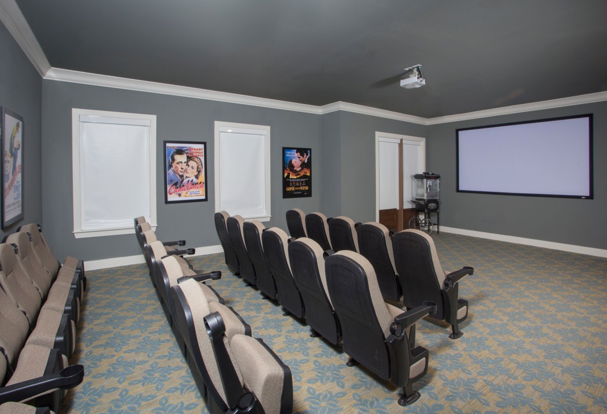 A cozy home theater room with rows of seats, a projector, and a screen.