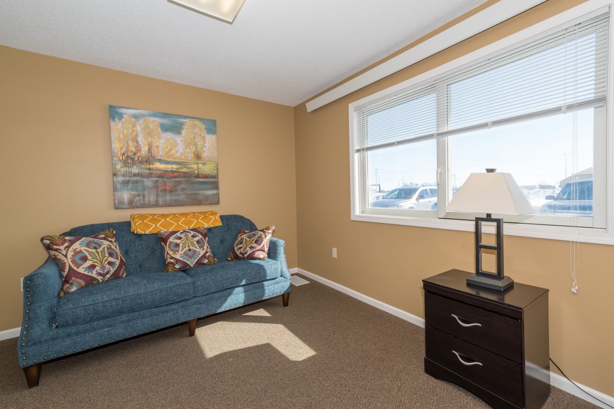 A cozy room featuring a sofa, artwork on the wall, and a window letting in natural light.
