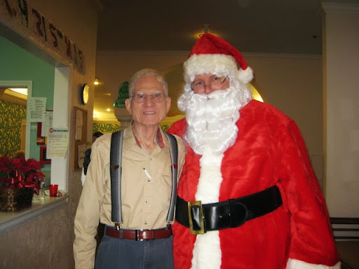 A cheerful moment captured during the holiday season with Santa Claus and an elderly gentleman.