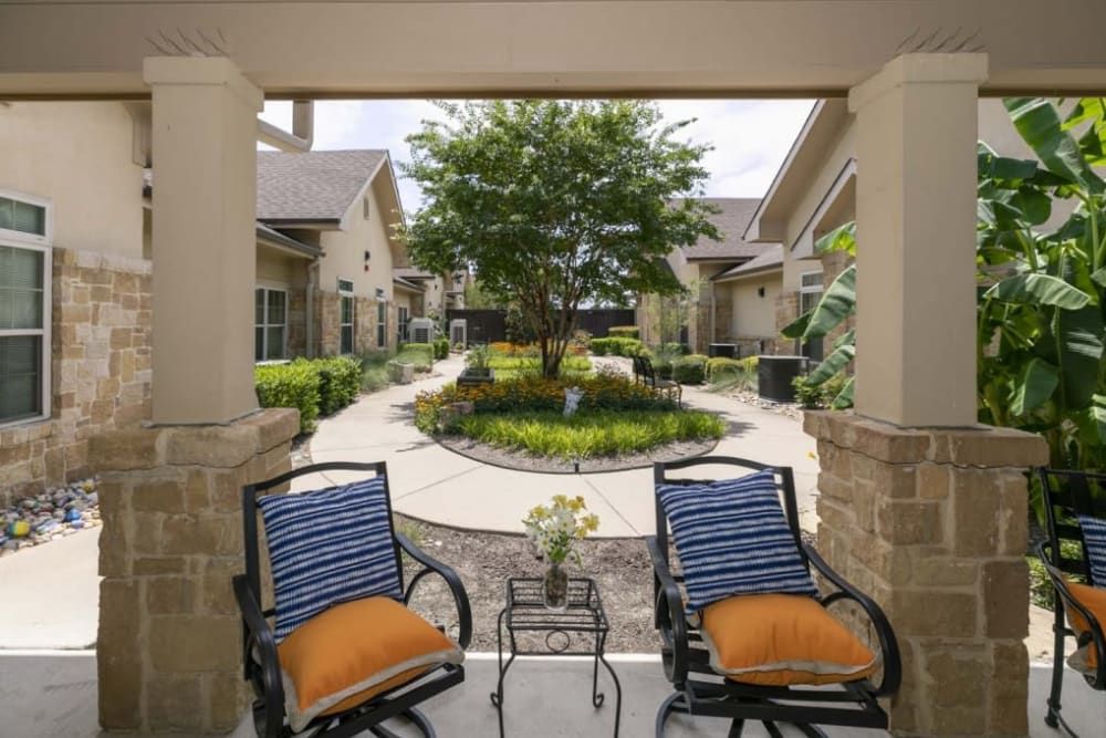 A cozy patio with two chairs overlooks a beautifully landscaped garden and pathway.
