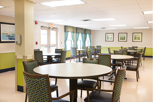 A spacious and well-lit dining area featuring round tables and comfortable chairs, perfect for social gatherings.
