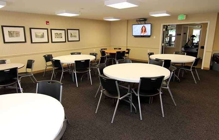 A conference room with round tables and chairs, equipped with a television.