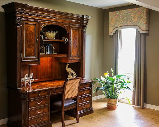 A beautifully designed home office featuring a wooden desk with an ornate shelving unit and lush indoor plants.