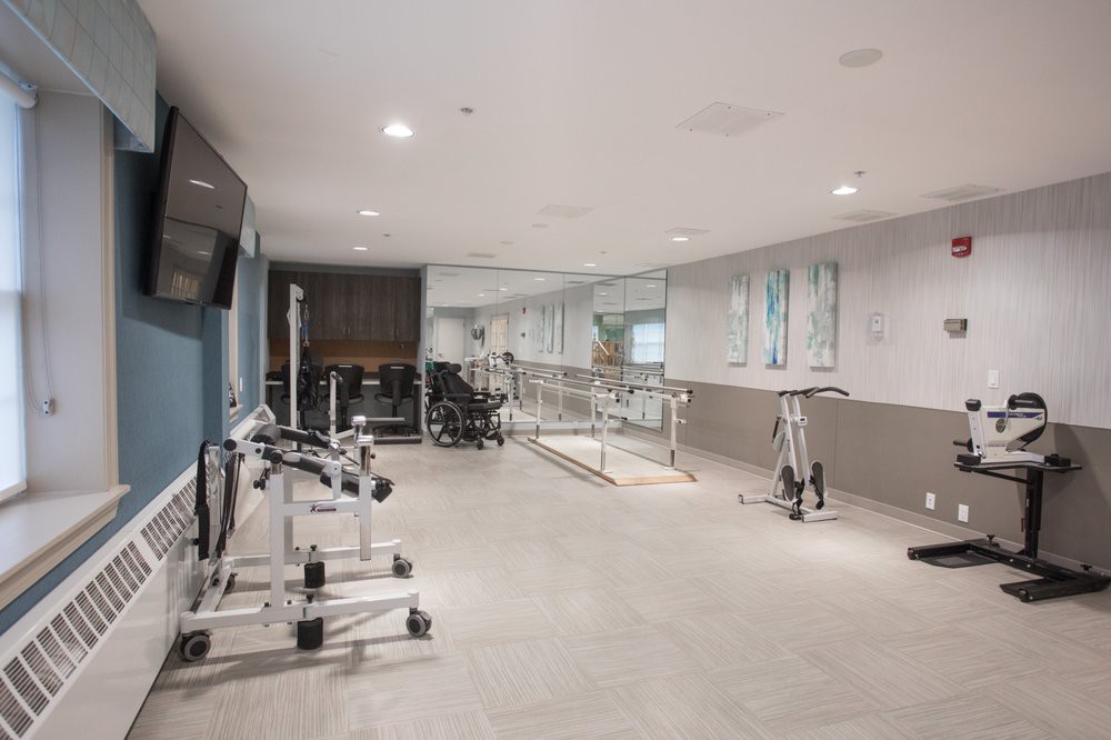 A well-equipped rehabilitation and physical therapy room featuring various gym equipment and large mirrors.