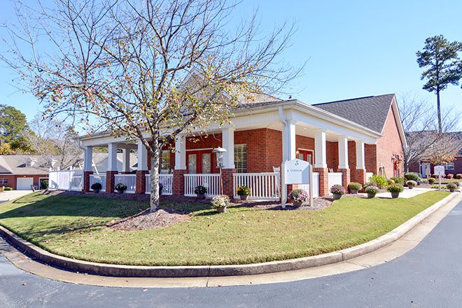 A suburban house with a large porch and landscaped yard.