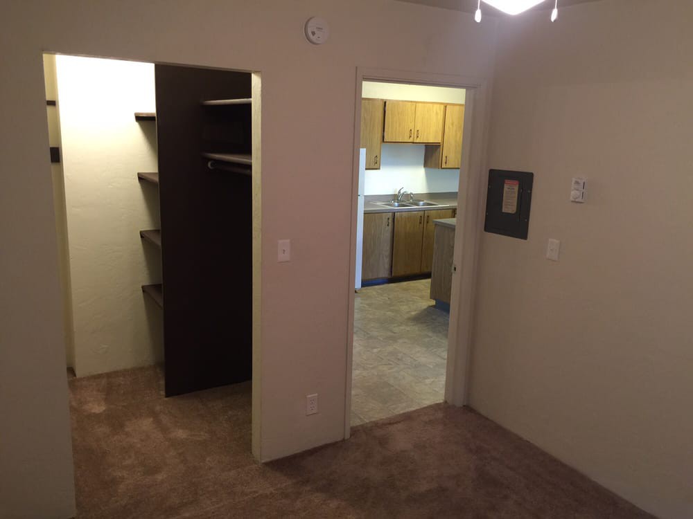 View of an apartment with a closet and kitchen area.