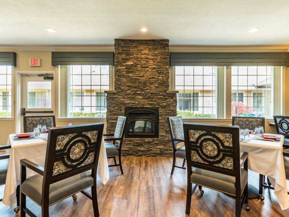 Cozy dining area with a central stone fireplace and large windows.