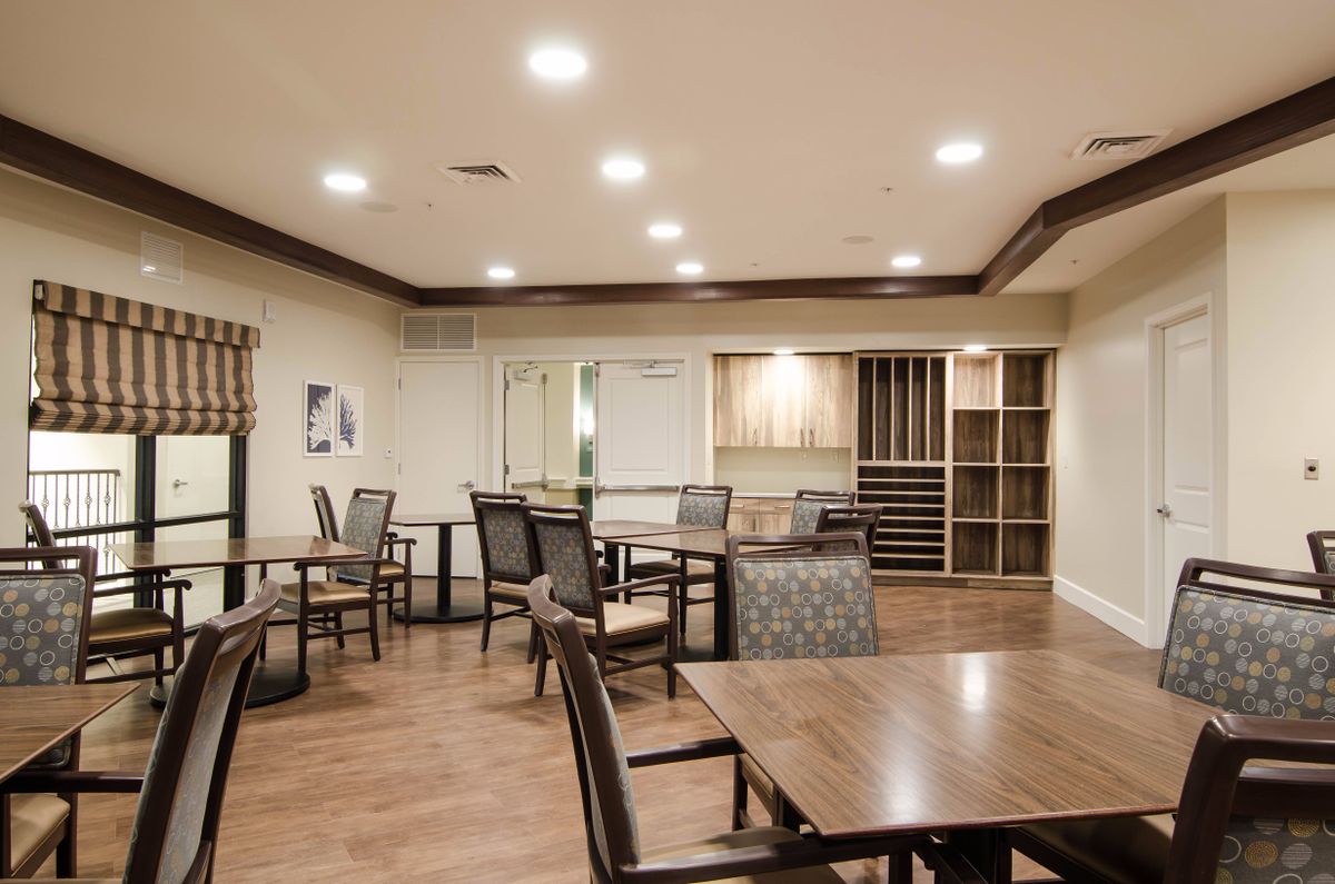 A cozy dining area with wooden tables and chairs, featuring warm lighting.