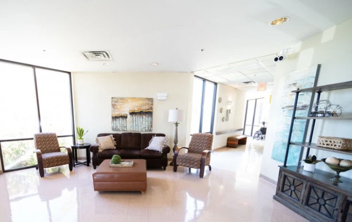 A modern living room with a sofa, armchairs, and large windows.
