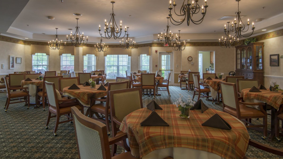 An elegant dining room with chandeliers and neatly set tables.