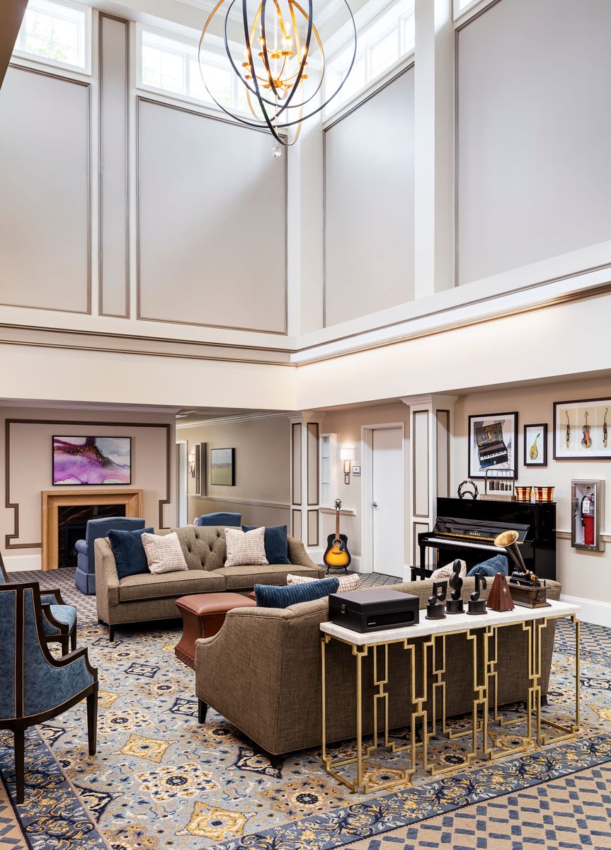A spacious and elegant living room with modern furniture, featuring a piano and guitars, complemented by artworks on the walls.