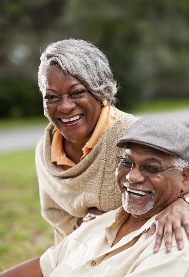 An elderly couple smiling and enjoying each other's company outdoors.