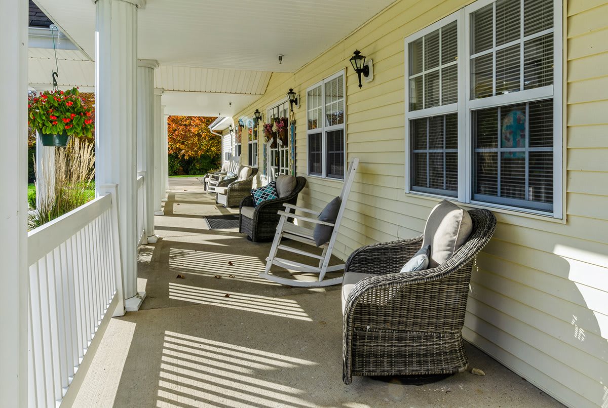 A peaceful porch with wicker chairs and a rocking chair, perfect for relaxing in the autumn afternoon.
