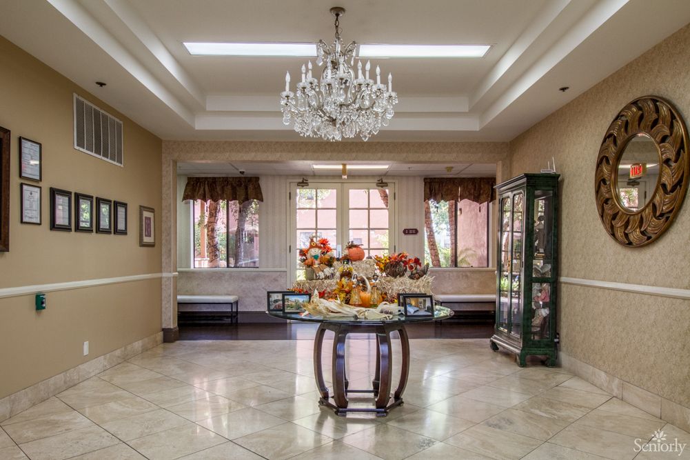An elegant room with a chandelier, featuring a central table adorned with a fruit display.