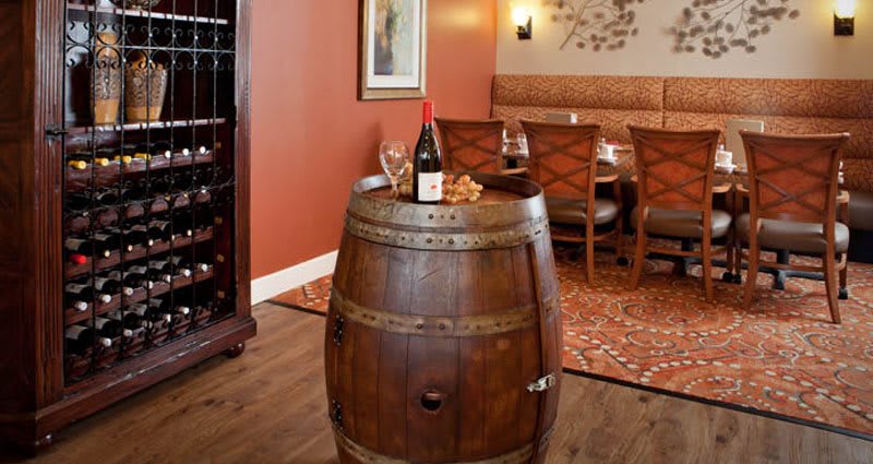 A cozy restaurant setting featuring a wine barrel table with a bottle of wine and glasses.