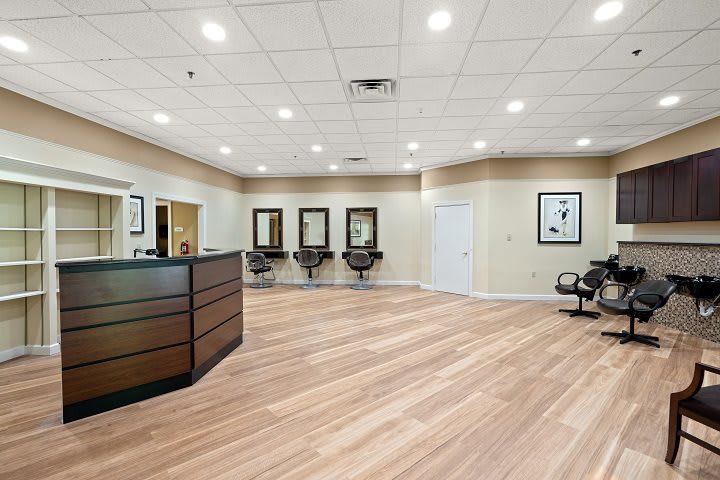 A modern hair salon interior with a reception desk and styling stations.