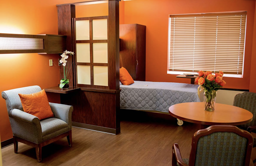A cozy and vibrant living space featuring an orange wall, wooden furniture, and a comfortable atmosphere.