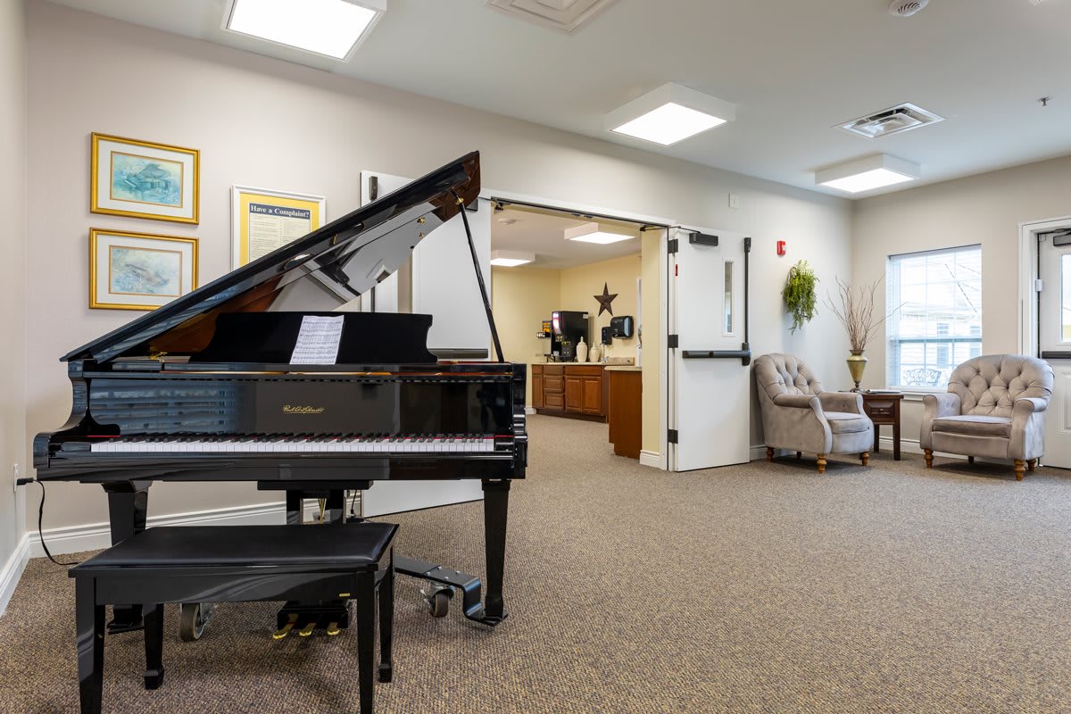 A bright music room featuring a grand piano and comfortable seating.