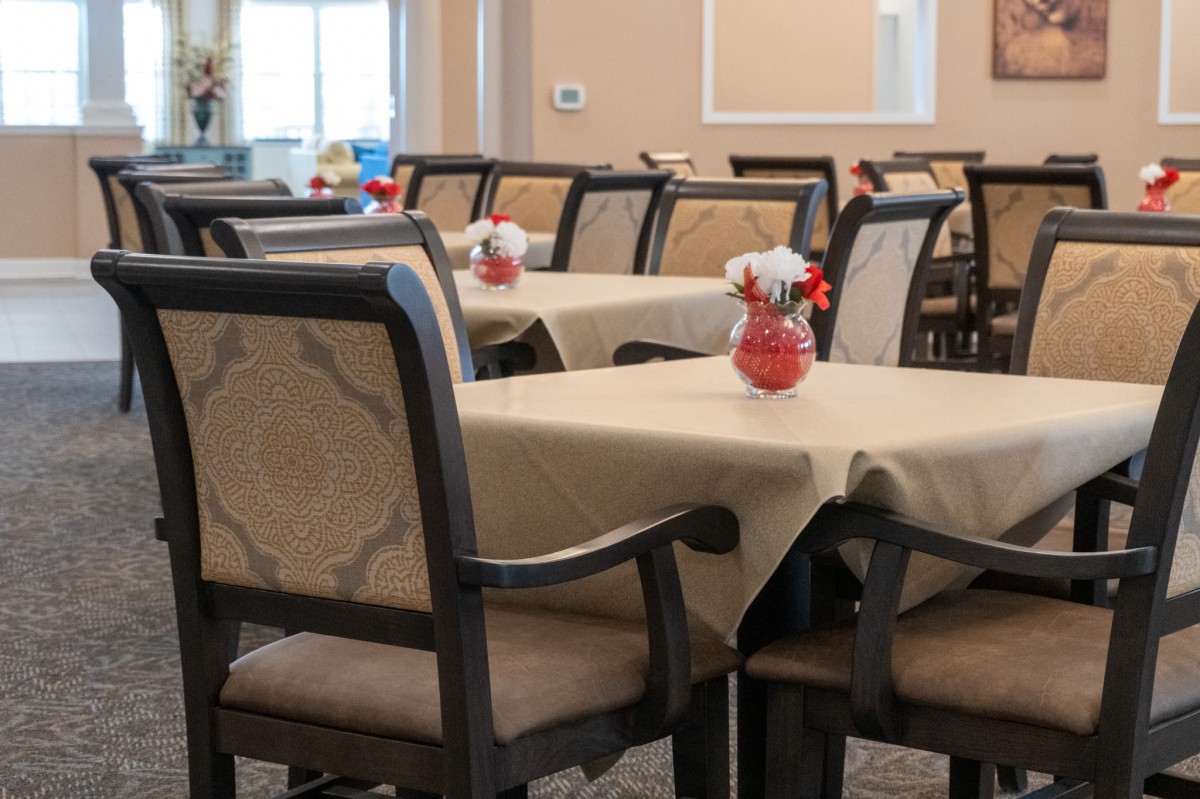 An indoor dining area with neatly arranged tables and chairs, adorned with tablecloths and centerpieces.